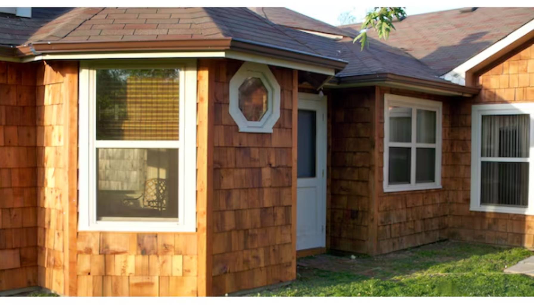 Small wooden shed with shingle siding and a white door.